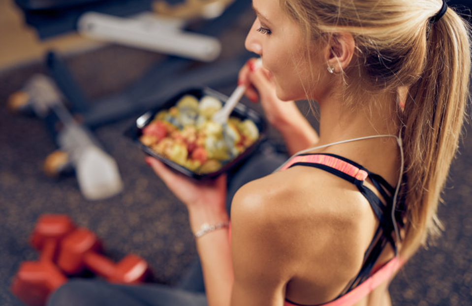 Top view of woman eating healthy food while sitting in a gym. Healthy lifestyle concept.